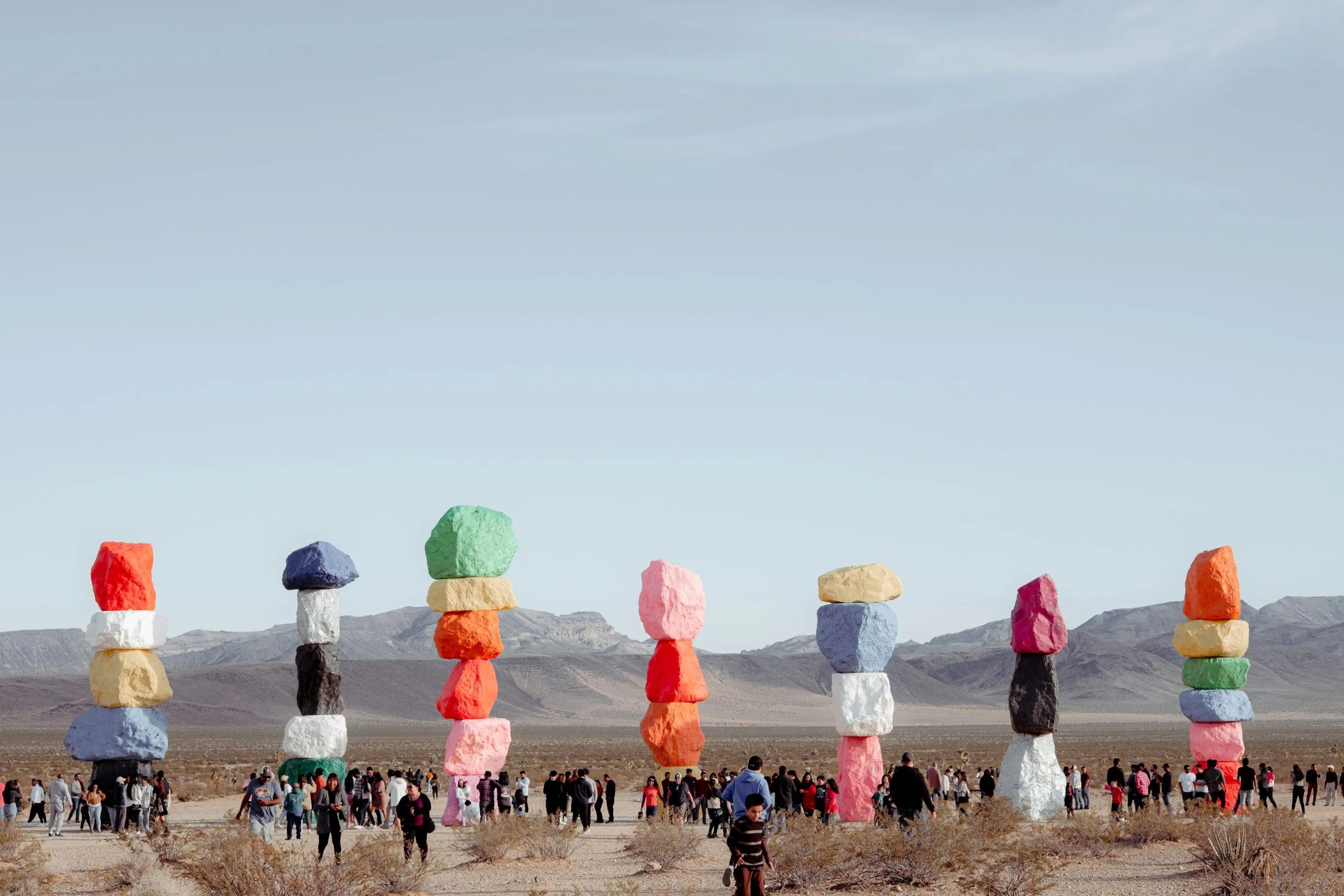a group of people at a beach with large colorful balloons