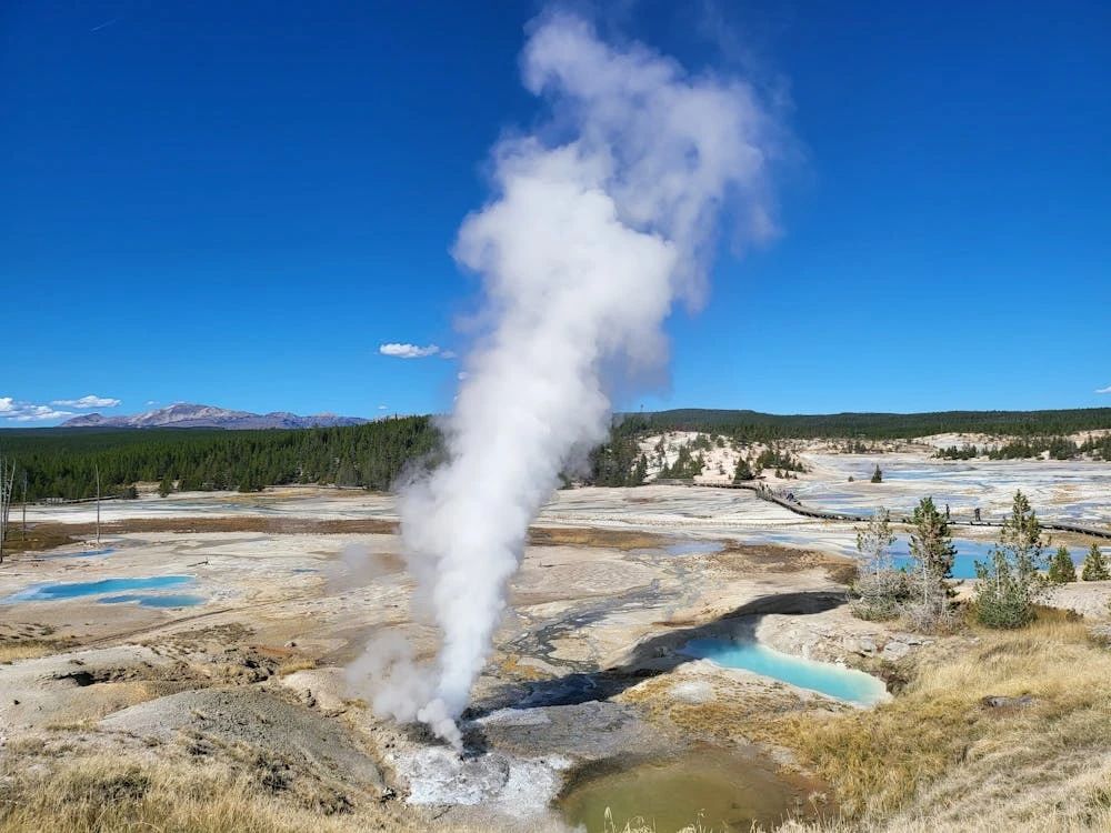 Free An aerial view of Norris Geyser Basin in Yellowstone National Park with steam rising under a clear blue sky. Stock Photo
